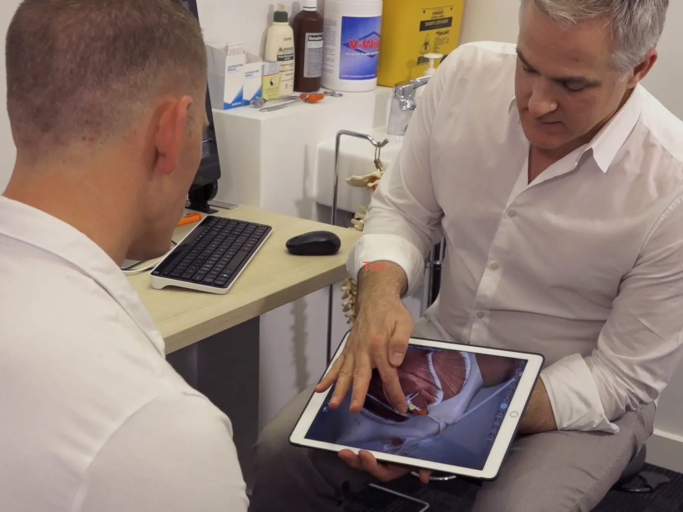 Nathan explaining pelvic anatomy on a tablet to a man in the consulting room