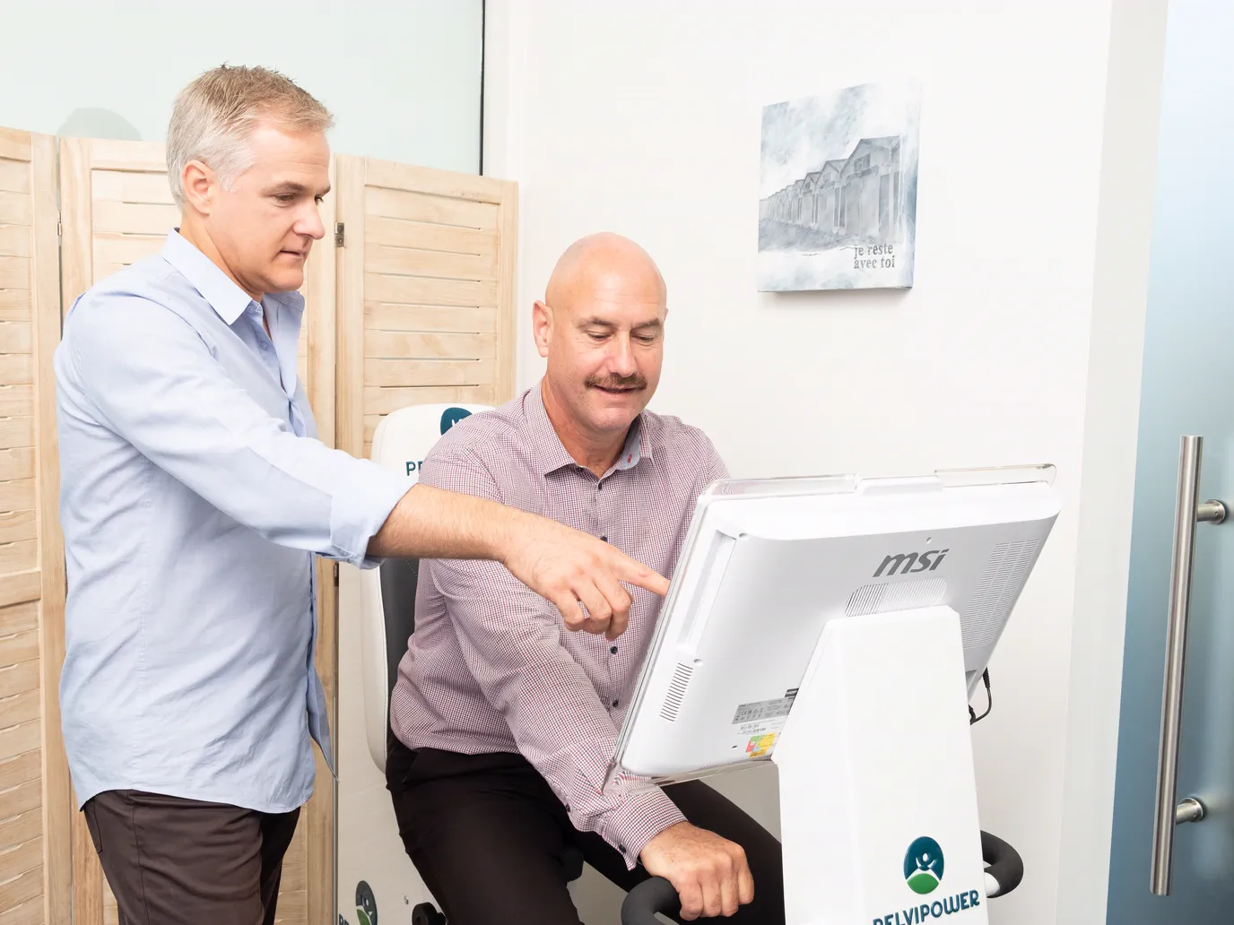 Nathan pointing out pelvic floor activity on the Bio-Feedback Trainer screen to a seated patient